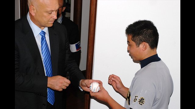 Cal Ripken signs a ball for a young Japanese fan.