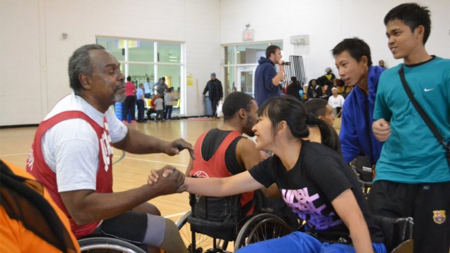 After playing a spirited round of wheelchair basketball, an Indonesian visitor is commended by her opponent.