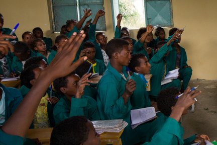 Children in a classroom raising their hands