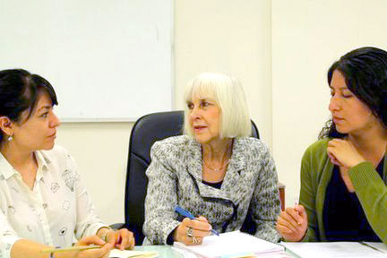 Three women sitting and talking in a classroom
