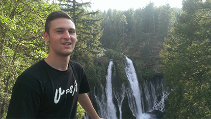 Dusan standing in front of a waterfall. 