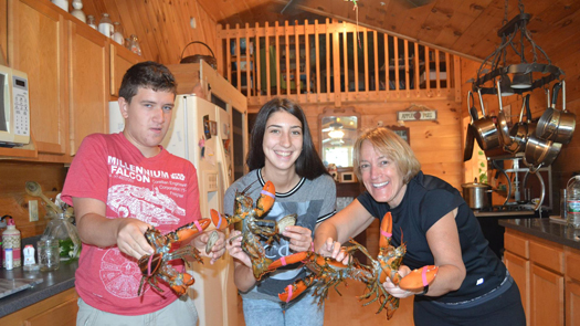 Three people holding lobsters and smiling