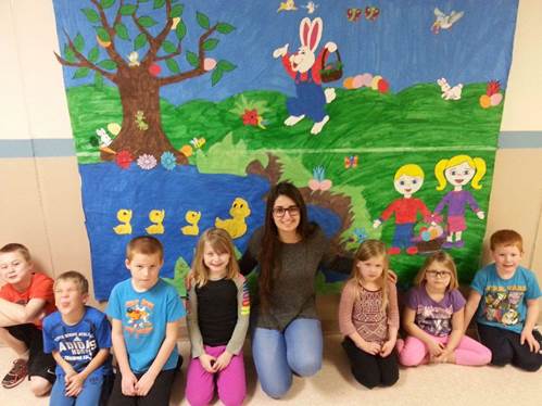 Young women siting with kids in a classroom