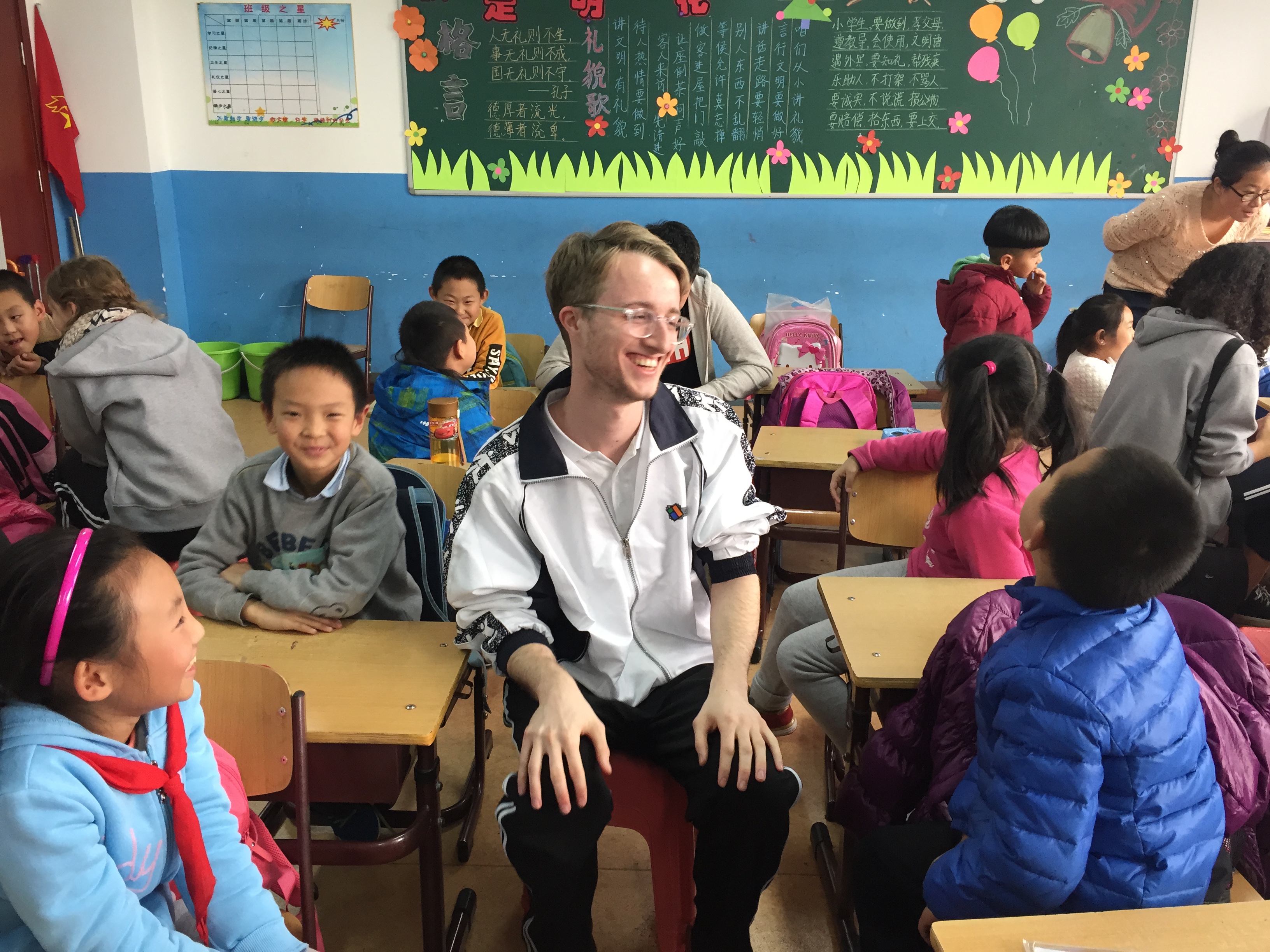 Ryan sits in the middle of young chinese children in a classroom