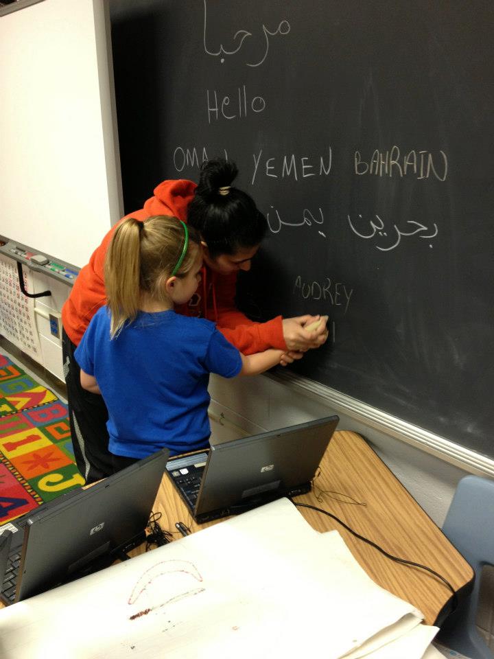 A participant in the volleyball coach program teaches a young girl how to write in Arabic during the group’s visit to an elementary school in Tennessee.