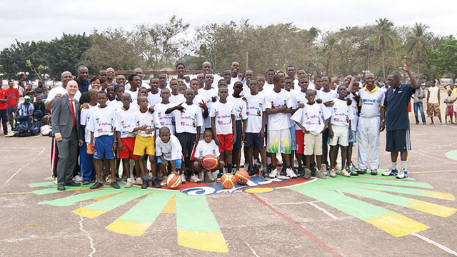 The participants gather for a photo with former NBA Player Bo Outlaw after a basketball scrimmage.