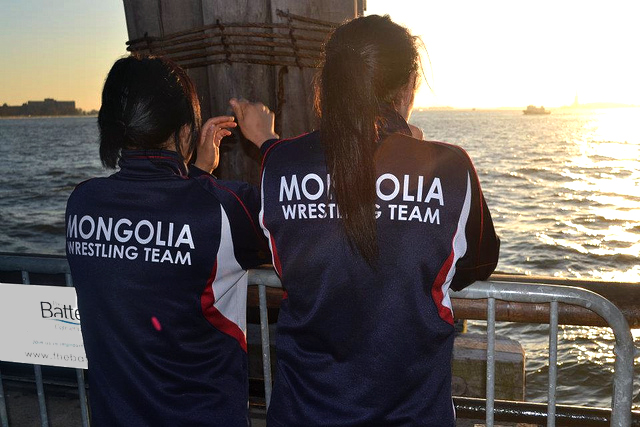 From a pier in New York Harbor, Mongolian wrestlers see the Statue of Liberty in the distance.