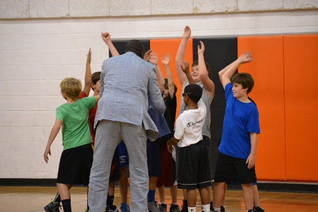 One of the South Sudanese coaches high-fives young American basketball players after a friendly scrimmage.