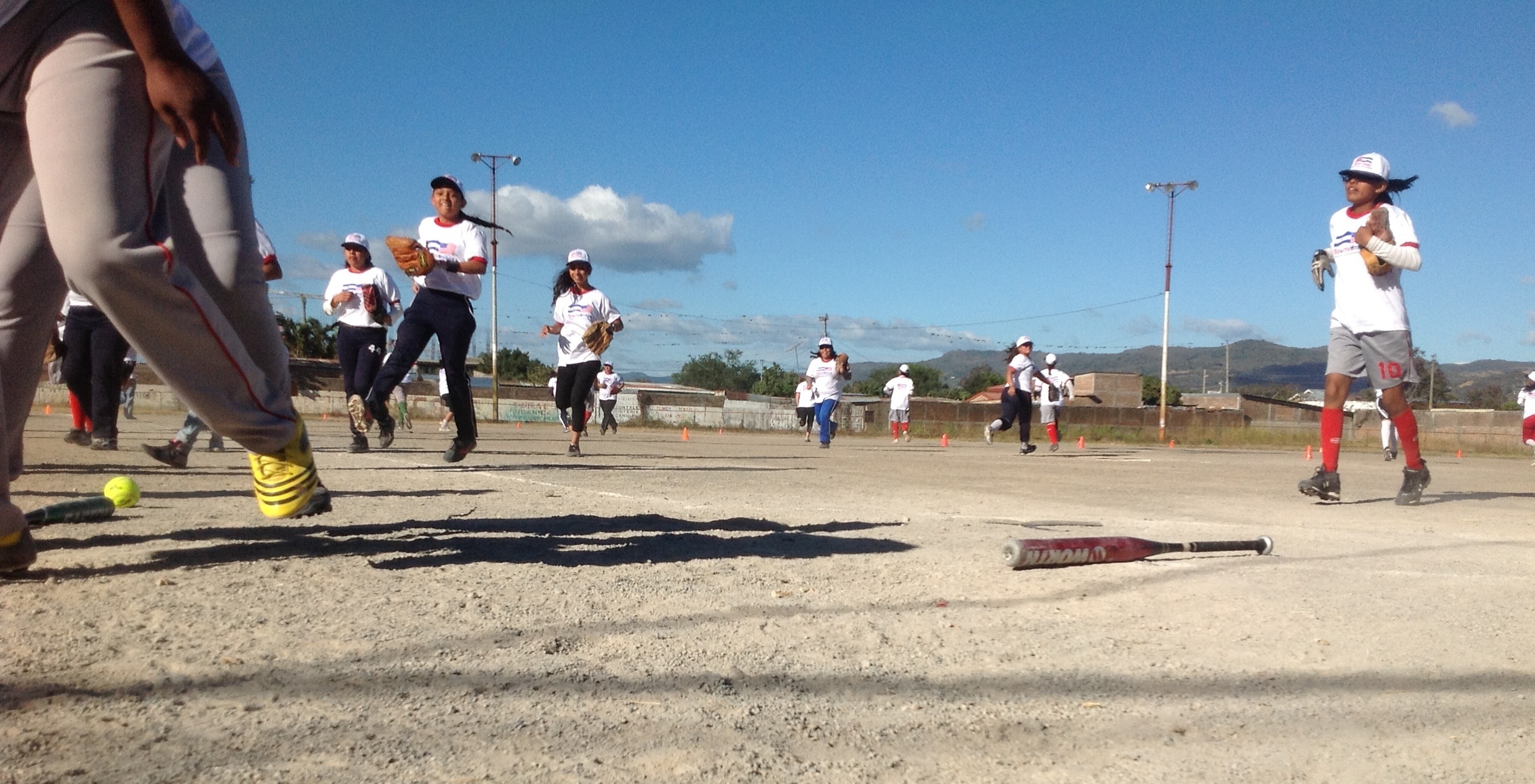 After a fun game of softball with the sports envoys, a team of teenage girls trot off the field.