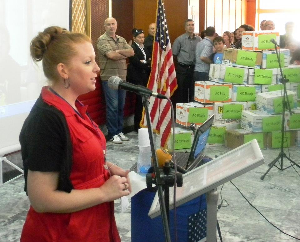 Fulbright English Teaching Assistant Jennifer Birdsall speaking at the American Corner Tetovo, where the 14,500 English books collected through donations were distributed. The pyramid of books can be seen in the background.