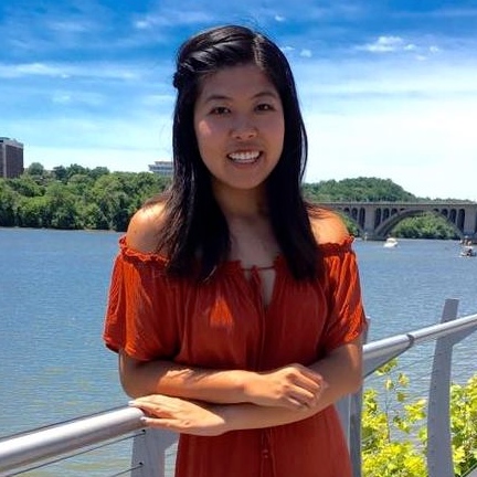 Girl smiling standing in front of a body of water
