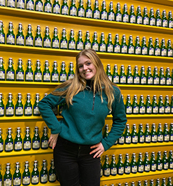 Leah standing in front of a wall of bottles