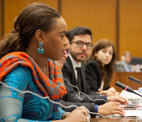 Woman participant sits in front of mic along side other participants as she ask a question
