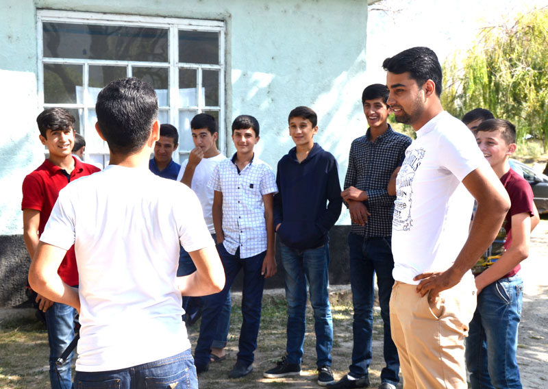 Young man stands smiling with a group of young boys