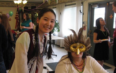 Zhyldyz having fun with a resident at her host community's senior care facility Mardi Gras party that she helped organize