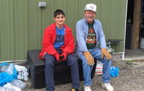 Boy in a red coat sitting to the left of an older man wearing denim