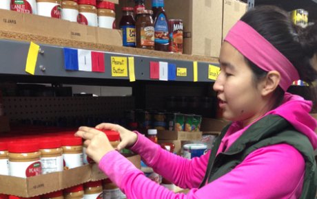 High school age girl stocking peanut butter at food pantry