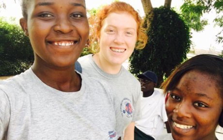 A red-headed girl smiling in a selfie in between two of her Senegalese girl friends.