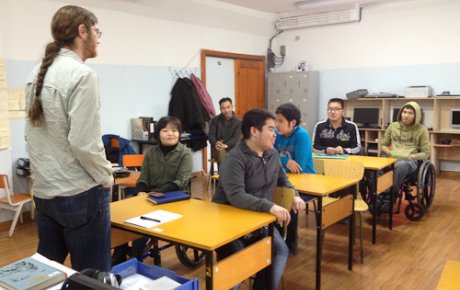 Teacher stands in front of classroom of students at desks