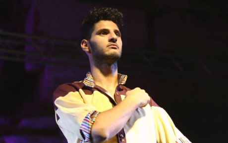 Young man stands proud with his arm across his chest