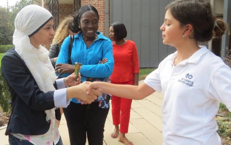 Women participant shaking hands with girl student during volunteer activity