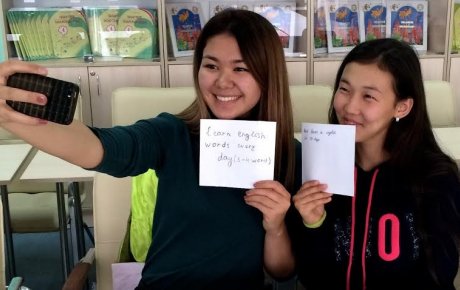 Girls taking a selfie with cell phone while holding up handwritten signs