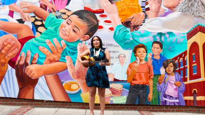 banner image of woman playing the guitar in front of a colorful mural