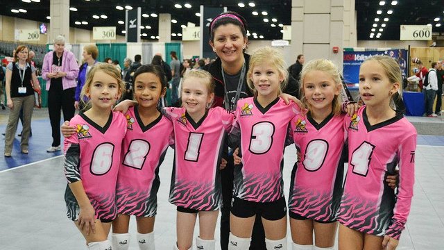 An Iraqi volleyball coach poses with girls after a day of volleyball exercises in Texas.