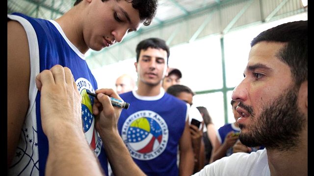 Teenage fans line up for Greivis Vasquez&#039;s autograph after a basketball session.