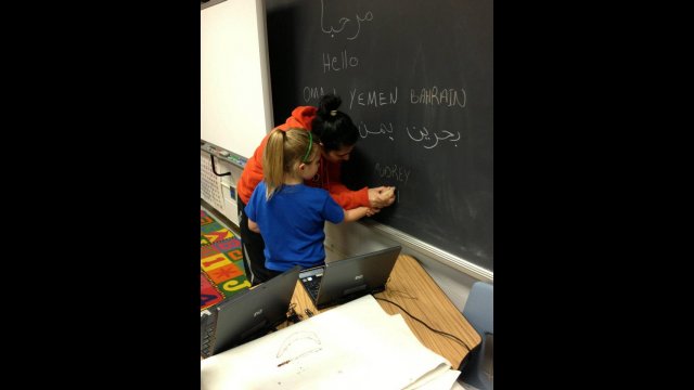 A participant in the volleyball coach program teaches a young girl how to write in Arabic during the group’s visit to an elementary school in Tennessee.