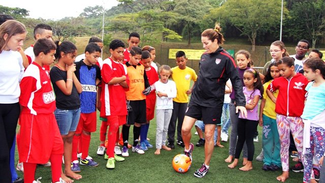 Julie Foudy shares her expert tips on kicking techniques with young female clinic participants in a neighborhood outside of São Paulo.