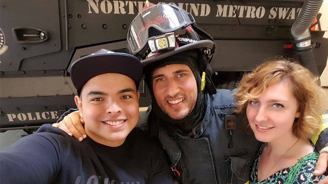 Two young people pose with a fire fighter