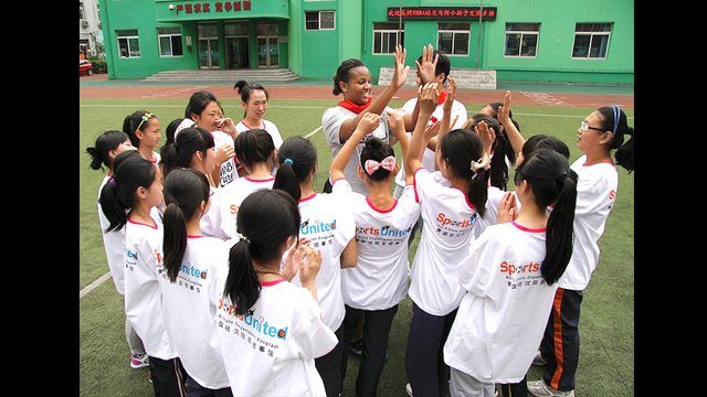 Tamika Williams “high fives” new friends at the Shenhe Migrant Workers Elementary School in China.