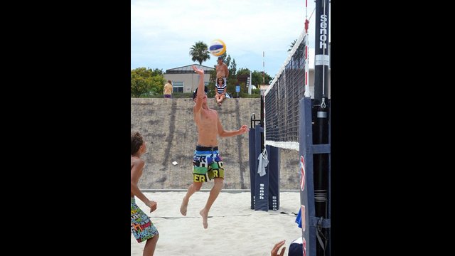 A young Russian athlete goes up for a hit while his American teammate watches.