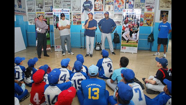 Barry Larkin and Joe Logan speak with young athletes before a baseball clinic in Ecuador.