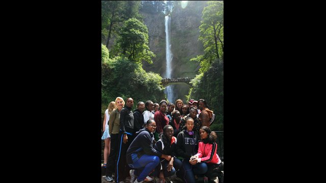 The track and field visitors visit a waterfall during their mountain hike in Oregon.