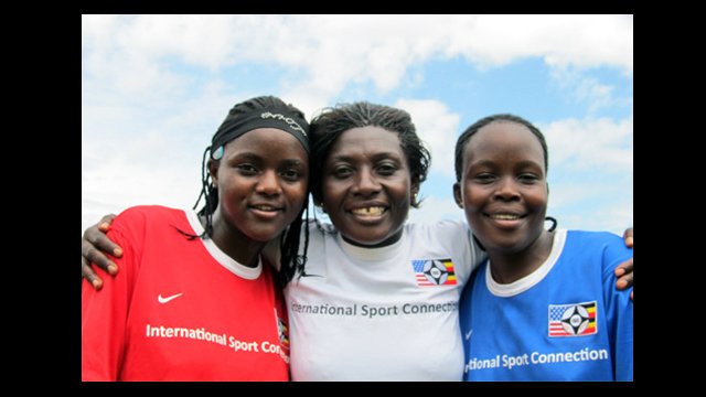 Ugandan soccer coaches dressed in red, white, and blue, pose for a photo in Kampala.