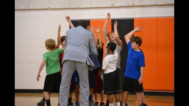 One of the South Sudanese coaches high-fives young American basketball players after a friendly scrimmage.