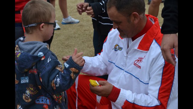 A coach visitor attaches a flag to a young American emerging athlete at a cross-training flag-football session. 