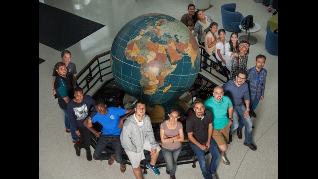 International students pose around a large globe statue