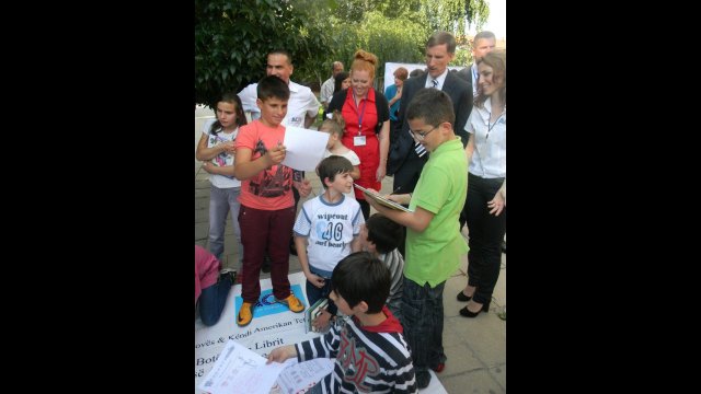 Fulbright English Teaching Assistant Jennifer Birdsall (in red) and U.S. Ambassador to Macedonia Paul Wholers watch at the American Corner in Tetovo as children collect books donated by communities in Nebraska.