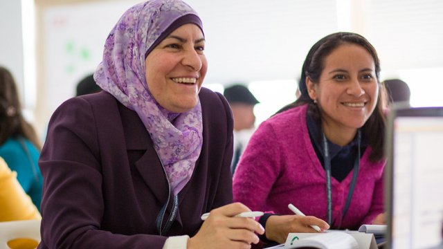 Photo of Teaching Excellence and Achievement (TEA) participants Taghreed Mubaideen, a Jordanian high school teacher and Suzy Huiracocha Panama, an Ecuadorian high school teacher, chat with classmates at Winthrop University