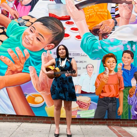 banner image of woman playing the guitar in front of a colorful mural