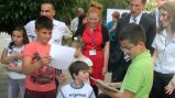 Fulbright English Teaching Assistant Jennifer  Birdsall (in red) and U.S. Ambassador to Macedonia Paul Wholers watch  at the American Corner in Tetovo as children collect books donated by  communities in Nebraska.