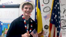 Young man in patirotic hat and lanai holding U.S. flag and miniature Statue-of-Liberty