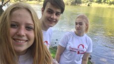 Close up of blonde girl on the left with two teens behind her in front of a river