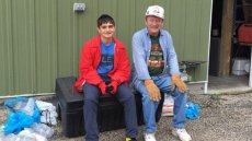 Boy in a red coat sitting to the left of an older man wearing denim