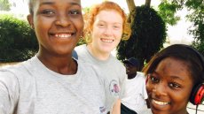 A red-headed girl smiling in a selfie in between two of her Senegalese girl friends.