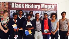 Group of people stand in front of Black History Month sign