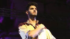 Young man stands proud with his arm across his chest